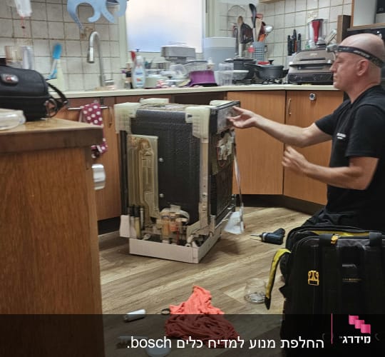 טכנאי מתקין מדיח כלים במטבח עם כלים על הרצפה